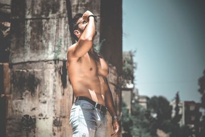 Midsection of shirtless young woman standing outdoors