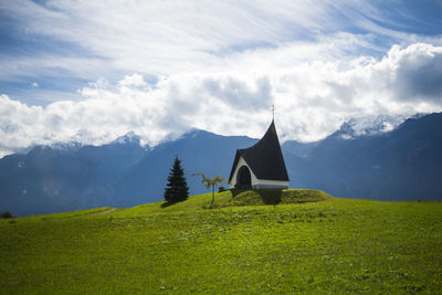 Chapel on green hill against mountains