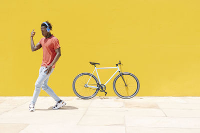 Energetic ethnic guy jumping near bicycle