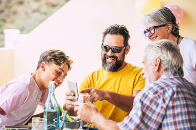 Cheerful family using mobile phone while having food on table