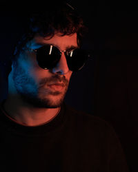 Portrait of young man wearing sunglasses against black background