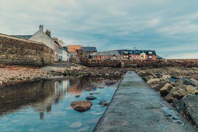 Buildings by river against sky