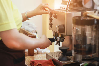 Midsection of woman preparing coffee in cafe