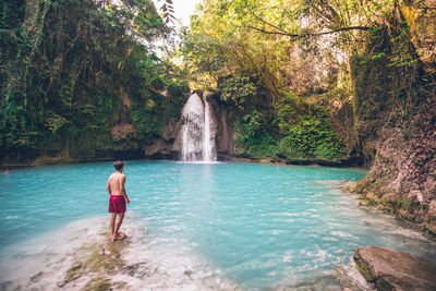 Man looking waterfall in forest