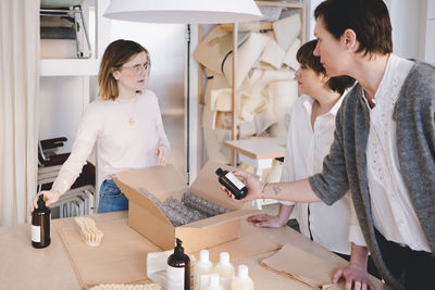 Female owners discussing over manufacturing objects at table in workshop