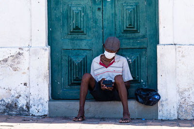 Full length of man sitting outside building