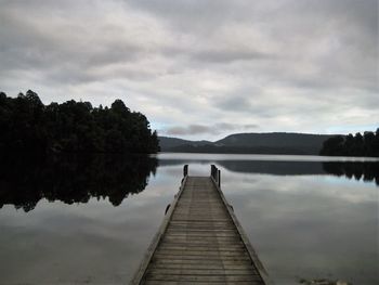 Pier on lake against cloudy sky