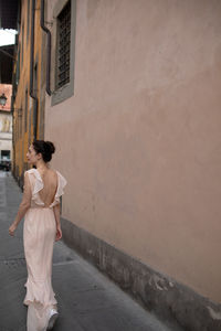 Rear view of beautiful women walking on street by building