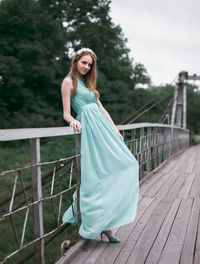 Full length portrait of woman standing on footbridge