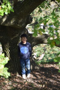 Portrait of boy standing on tree trunk