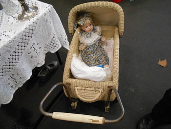 High angle view of doll in wicker baby carriage