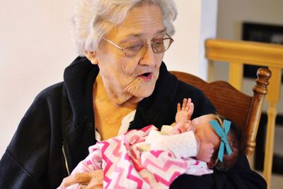 Grandmother with grandchild sitting on chair at home