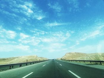 Country road along landscape against sky