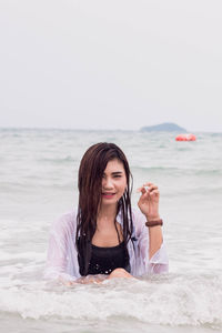 Portrait of smiling young woman on beach against sky