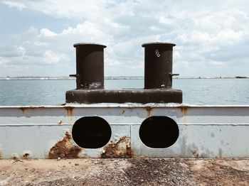 Rusty metallic structure on sea shore against sky