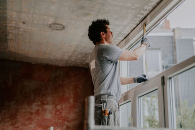 One builder is measuring a window frame with a ruler. person