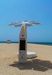 Lifeguard hut on beach against clear blue sky