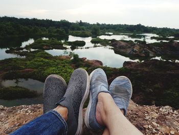 Low section of person on rock by lake