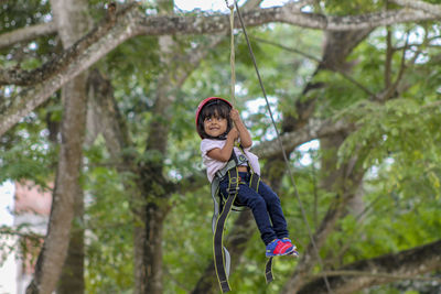 Low angle view of girl on zip line against tree