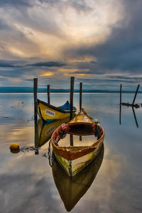 Boat moored on beach against sky during sunset