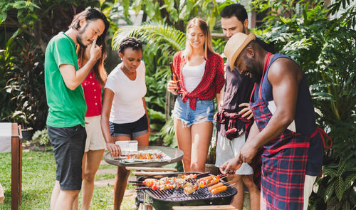 Friends enjoying barbecue while standing outdoors