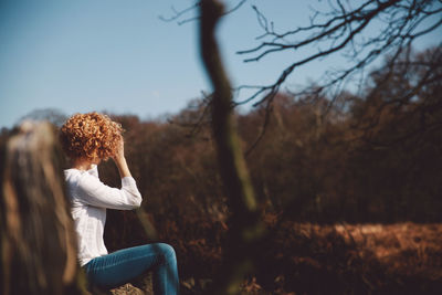 Woman sitting on field against clear sky