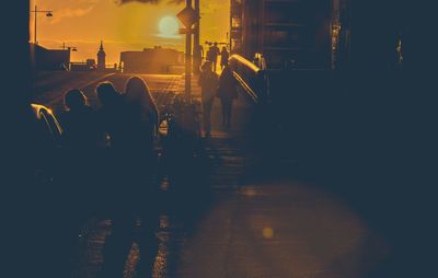 Silhouette people walking on illuminated street at night