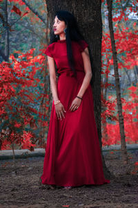 Midsection of woman standing by tree against red wall