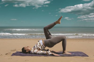 Female athlete performing pilates exercise on the beach