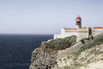 Lighthouse on beach against clear sky