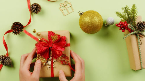 Girl's hands place a gift for christmas on the green table