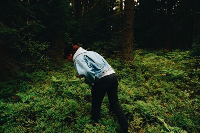 Rear view of woman standing on plants at forest