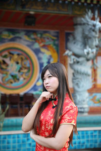 Beautiful young woman looking away while standing outdoors