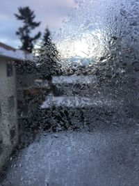 Close-up of wet window against sky