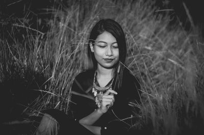 Young woman sitting amidst grass on field