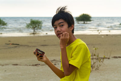Portrait of mature man using mobile phone at beach