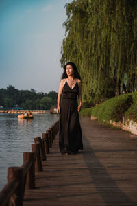 Portrait of woman walking by water against plants