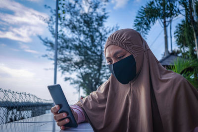 Midsection of man using mobile phone against sky