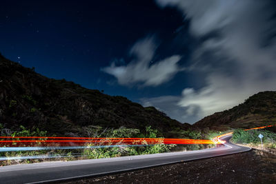 Light trails on road against sky at night