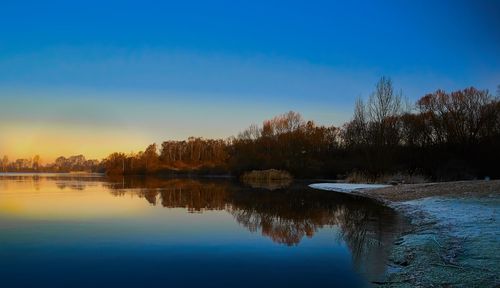 Reflection of trees in lake during sunset