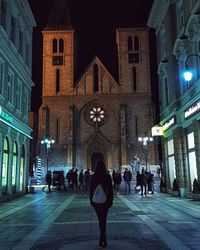 People at illuminated temple in city at night