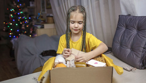 Full length of girl sitting in box at home
