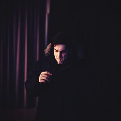 Portrait of young man standing in dark room