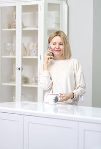 Young woman using mobile phone while standing in bathroom