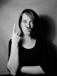 Portrait of woman gesturing against wall at home