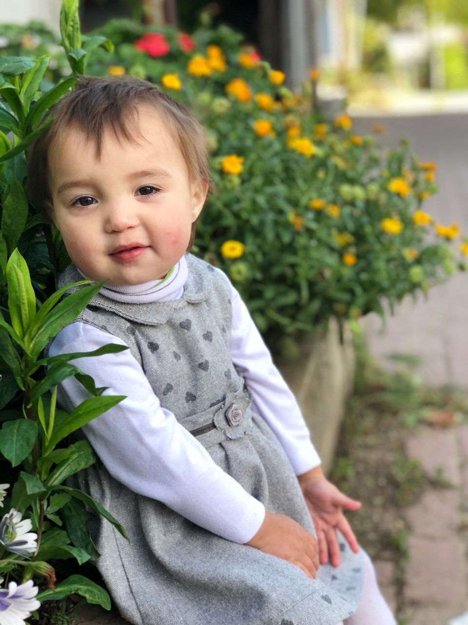 PORTRAIT OF CUTE GIRL STANDING ON FLOWERING PLANTS