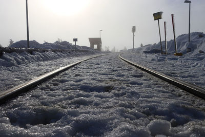 Surface level of railroad tracks against sky during winter