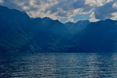 Scenic view of sea by mountains against sky