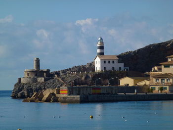 Buildings at waterfront against cloudy sky