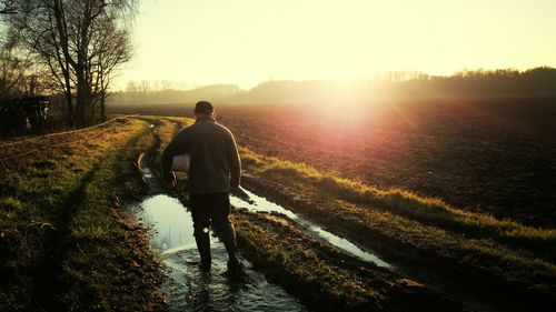 Rear view of farmer walking on dirt road